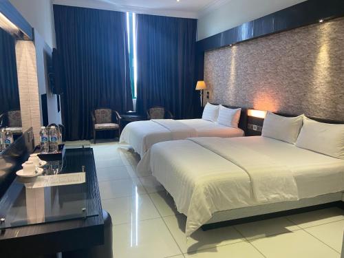 una camera d'albergo con due letti e un tavolo di OYO 90934 Tong Villion Hotel a Muadzam Shah