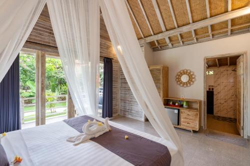 - une chambre avec un lit et une moustiquaire dans l'établissement Le Biu garden View, à Nusa Lembongan