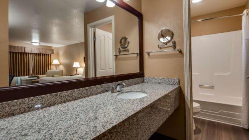 Best Western Country Inn في فورتونا: حمام مع حوض ومرآة كبيرة