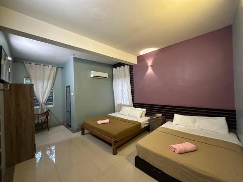 巴東馬士力的住宿－OYO 90938 The Nk Langkawi，一间卧室设有两张床和紫色墙壁