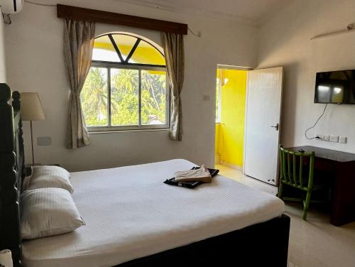 a bedroom with a large bed and a window at Easy Living Guesthouse in Orlim