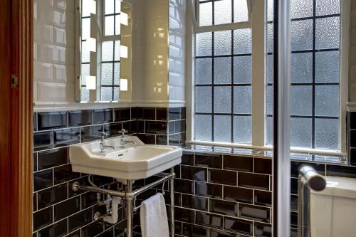 a bathroom with a sink and a mirror and windows at Best Western Plough and Harrow Hotel in Birmingham