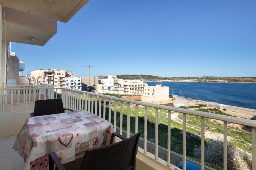balcón con mesa y vistas al agua en Cosy1 Bedroom Apartment with Balcony & Sea Views - Close to Mellieha Bay, en Mellieħa