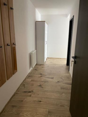 a hallway with a white wall and a wooden floor at Rado Apartments in Svit