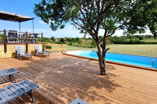 une terrasse en bois avec un arbre et une piscine dans l'établissement Le Lot, à Orniac