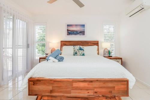 a bedroom with a large wooden bed with white sheets at Beach home in the heart of Agnes in Agnes Water