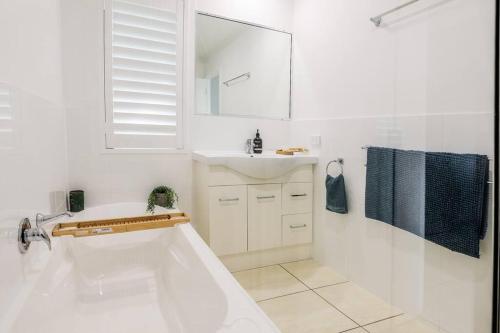 a white bathroom with a sink and a mirror at Beach home in the heart of Agnes in Agnes Water