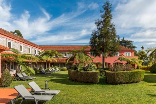 a courtyard with chairs and trees and a building at Enotel Santo da Serra in Santo António da Serra