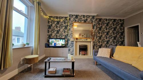 a living room with a couch and a tv at Brodie's Hideaway: Stylish two-bed Amble apartment in Amble