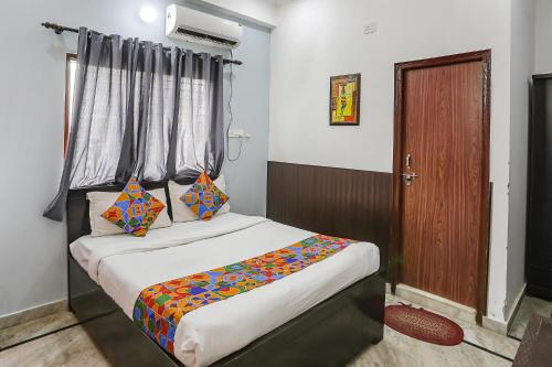 1 dormitorio con 1 cama con sábanas coloridas y ventana en FabExpress Samira Residency, Near Botanical Garden, en Noida