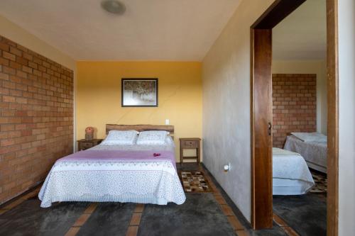 een slaapkamer met een bed en een bakstenen muur bij Apartamento na Fazenda c/ Piscina Termica in Palmeira