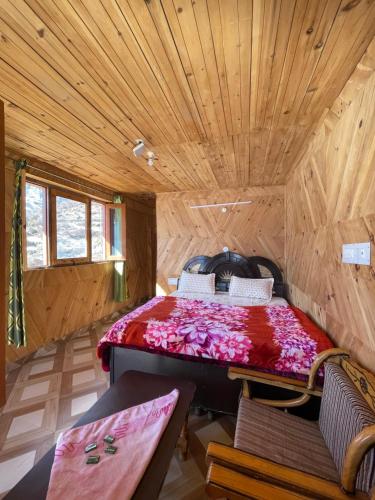 a bed in a room with a wooden ceiling at Pahadi Bliss Hostel ,Tosh in Tosh
