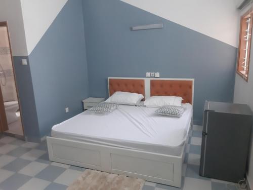 a bedroom with a white bed with a blue wall at Cotonou appart in Cotonou