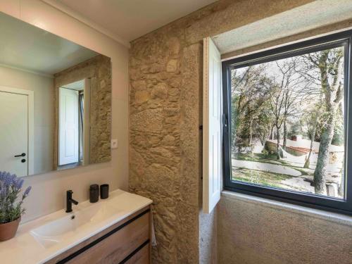 baño con lavabo y ventana grande en Casa Da Romeira Country House, en Freixieiro de Soutelo