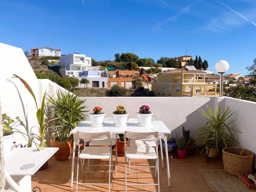 een witte tafel en stoelen op een balkon met planten bij Penthouse Oceaview Apartment in Cala del Moral