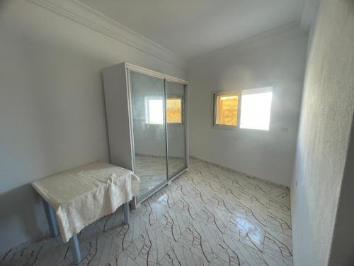 Dieses weiße Zimmer verfügt über einen Glasschrank und einen Tisch. in der Unterkunft Summer Rental in Nabeul