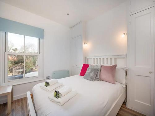 Dormitorio blanco con cama blanca grande y almohadas coloridas en Stylish Flat Centrally Located I Pass The Keys en Twyford