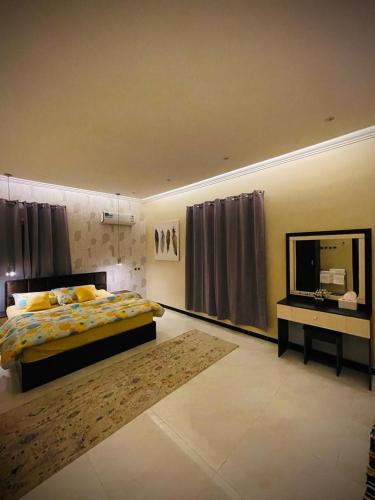 um quarto com uma cama, um espelho e uma televisão em Abha Jacaranda em Abha
