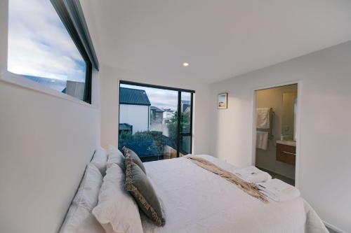 a white bedroom with a large bed and a window at The little Gem at Merivale -1km to Central city in Saint Albans