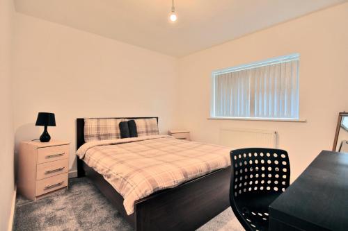 a bedroom with a bed and a chair and a window at Butlers Meadow House, Sleeps 5, near Blackpool Tower, BAE System, Free Parking - by NMB Property in Weeton