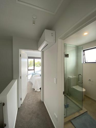 a bathroom with a glass shower and a bedroom at The little Gem at Merivale -1km to Central city in Saint Albans