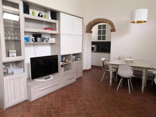 a living room with a tv and a table with chairs at Empoli Campagna, Appartamento Indipendente con giardino 500 mq e piscina privati in Empoli