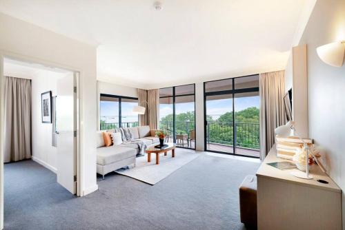 a living room with a couch and a table at Corner Balcony Suite on the Esplanade with Pool in Darwin