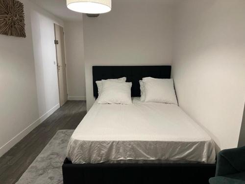 une chambre avec un lit avec des draps blancs et des oreillers dans l'établissement Ouly, à Honfleur