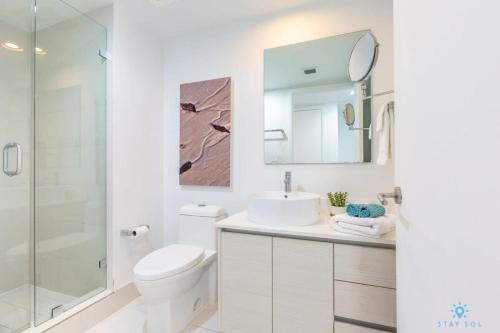 a bathroom with a toilet and a sink and a mirror at Spectacular View with Balcony, Pool, Near Beach in Hallandale Beach