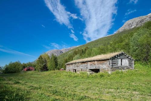 an old barn in a field with a mountain at Seterstue i Beiarn - Beiarn Lodge in Beiarn