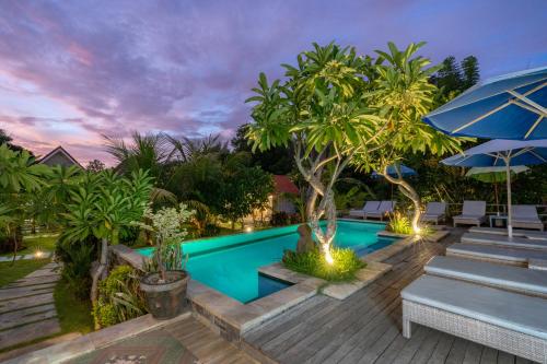 a pool with a wooden deck with benches and umbrellas at Le Biu garden View in Nusa Lembongan