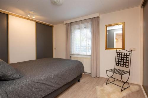 ein Schlafzimmer mit einem Bett, einem Fenster und einem Stuhl in der Unterkunft Klein Doornroosje (gelegen op Doornroosje landgoed) in Ermelo