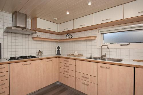 een keuken met houten kasten en een wastafel bij Klein Doornroosje (gelegen op Doornroosje landgoed) in Ermelo
