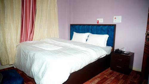 a bedroom with a large bed with a blue headboard at Pokhari Cottage Private Limited in Bahāsi