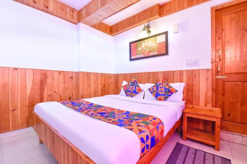sypialnia z dużym łóżkiem i drewnianymi ścianami w obiekcie FabHotel Elavali Valley w mieście Manāli