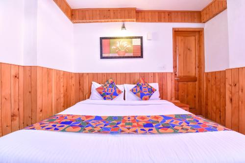 a bedroom with a white bed with wood paneling at FabHotel Elavali Valley in Manāli