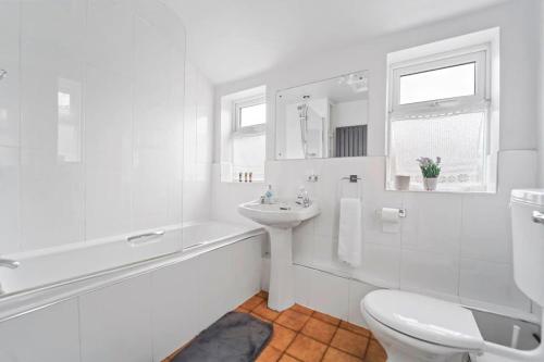 een witte badkamer met een wastafel en een toilet bij 4 Bed Homely Retreat - Wolverhampton in Wolverhampton