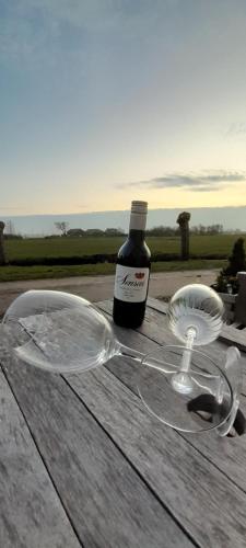 a bottle of wine and glasses on a wooden table at Stacaravan op de paardenboerderij Sneek in Sneek