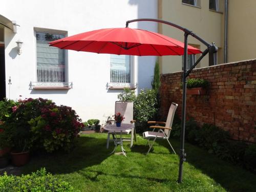a red umbrella and a table and chairs in a yard at Ferienwohnungen Haus Leonore in Stendal