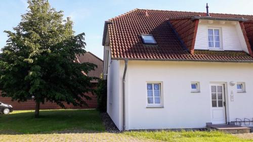 a white house with a tree next to it at Ferienwohnung Sonne in Neddesitz