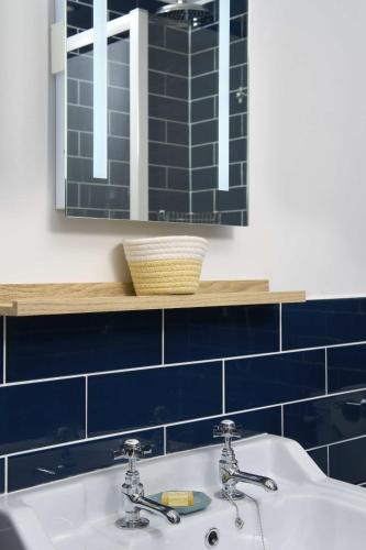 a bathroom with a sink and a mirror and blue tiles at The White Hart Hotel in Modbury