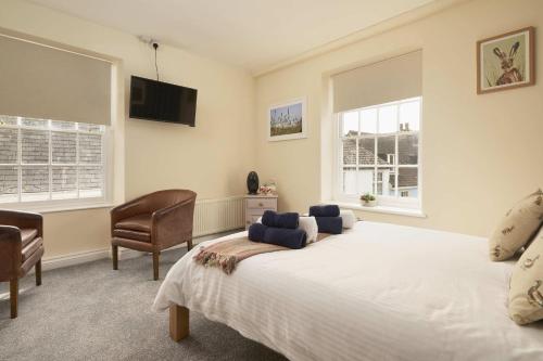 a bedroom with a large white bed and two windows at The White Hart Hotel in Modbury