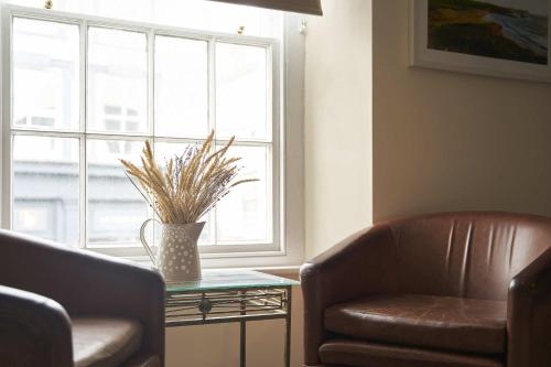 a living room with a couch and a chair and a window at The White Hart Hotel in Modbury