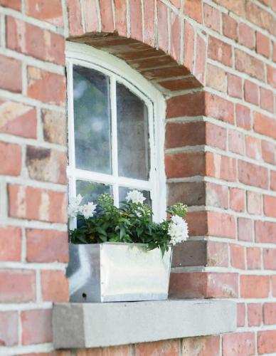 a window with flowers in a brick wall at Haus am Holder in Böhme