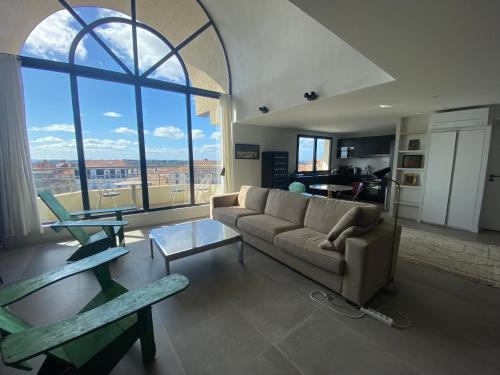 un salon avec un canapé et une grande fenêtre dans l'établissement Appartement standing sur le toit avec vue panoramique et rooftop, à Béziers