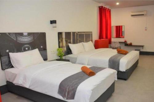 2 camas en una habitación de hotel con cortinas rojas en Hotel Ventura en Kangar