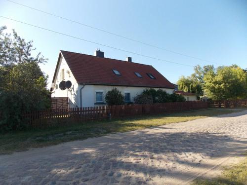 uma casa branca com um telhado vermelho e uma cerca em Ferienwohnung Mohnblume em Gerswalde