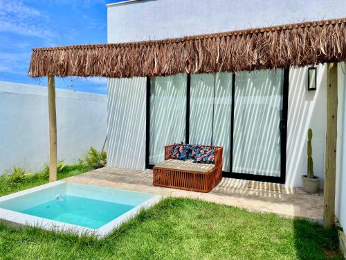 een huis met een zwembad en een rieten dak bij Casa privativa na Vila Ser tão zen #02 in Tibau do Sul