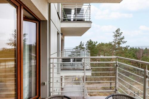 a balcony with a view of the woods from a house at Porta Mare - Apartment with Sea View Balcony & Parking by Renters in Dziwnówek