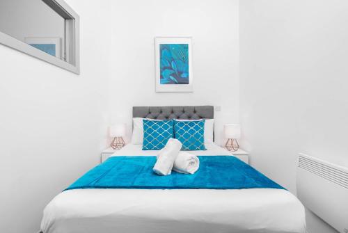 a white bedroom with a blue bed with two towels at Stylish Brierley Hill - 1 Bed Apt - Free Parking - Netflix & Wifi - 305O in Brettell Lane